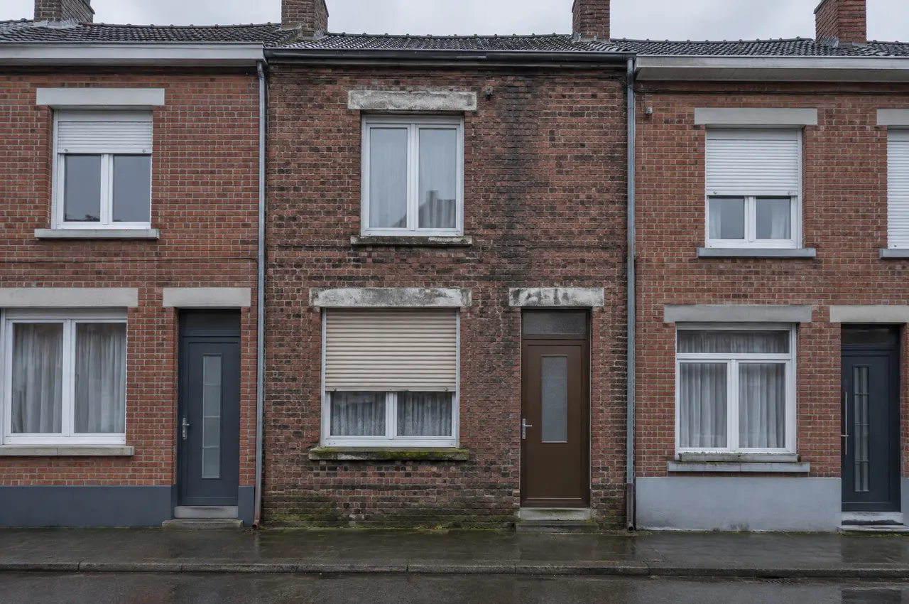 Maison de ville de 1905 à Roubaix, brique patinée, fenêtres en PVC blanc, volet roulant à demi baissé, dans une rangée de maisons